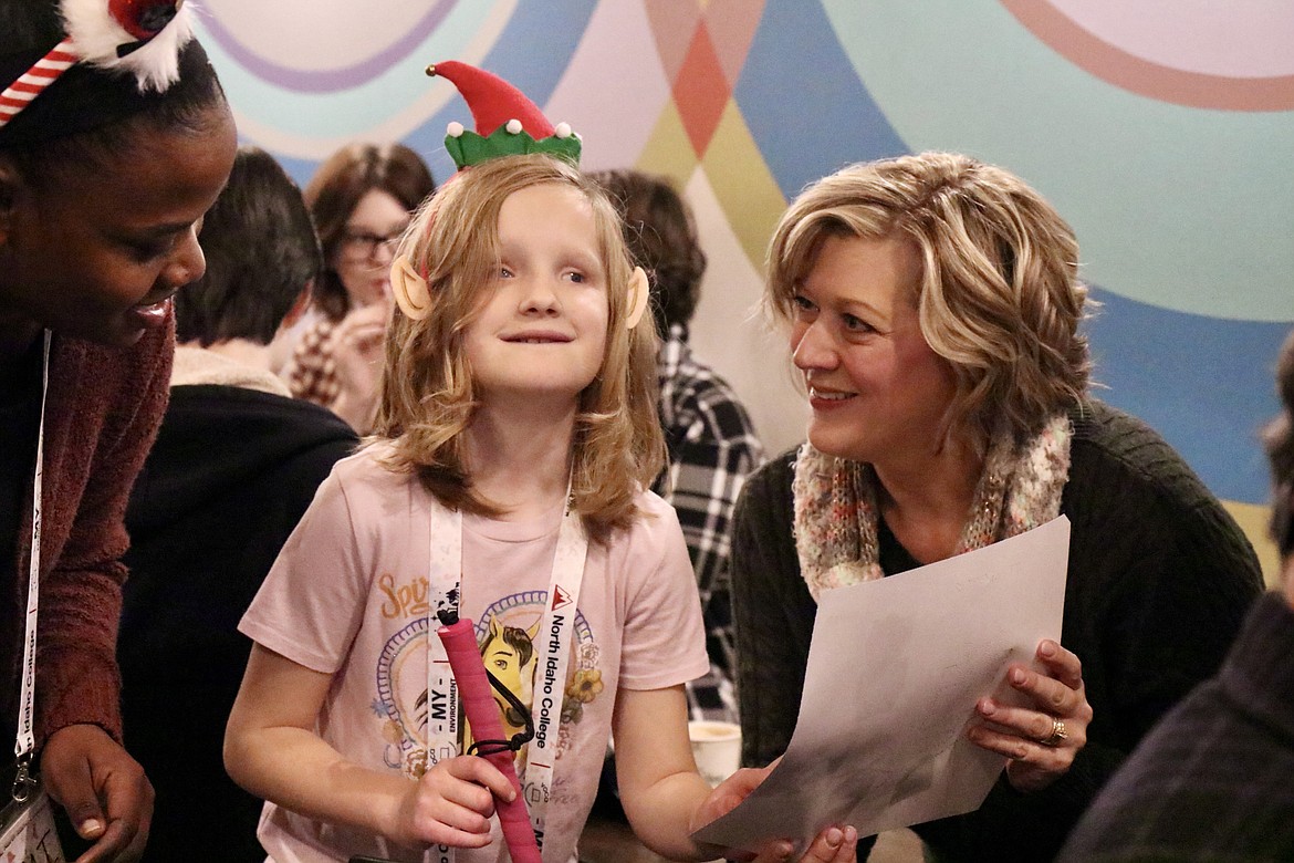 Ten-year-old Emilia Paulding, a visually impaired student, hands a hand-decorated Christmas card to Rhonda McCann of Post Falls at Evans Brothers Coffee Roasters on Saturday. HANNAH NEFF/Press