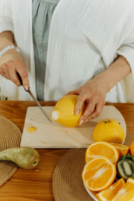 A woman is cutting a lemon in the kitchen, preparing fresh juice. 